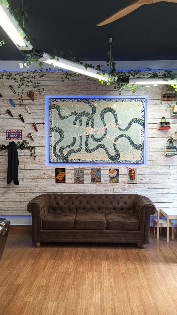 Sala de espera con sofá Chesterfield y mosaico en la pared en Hidalgo Junior.